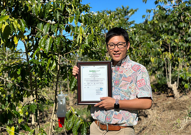 GGAP認定証を掲げるUCCハワイコナコーヒー直営農園の小林司ゼネラルマネージャー