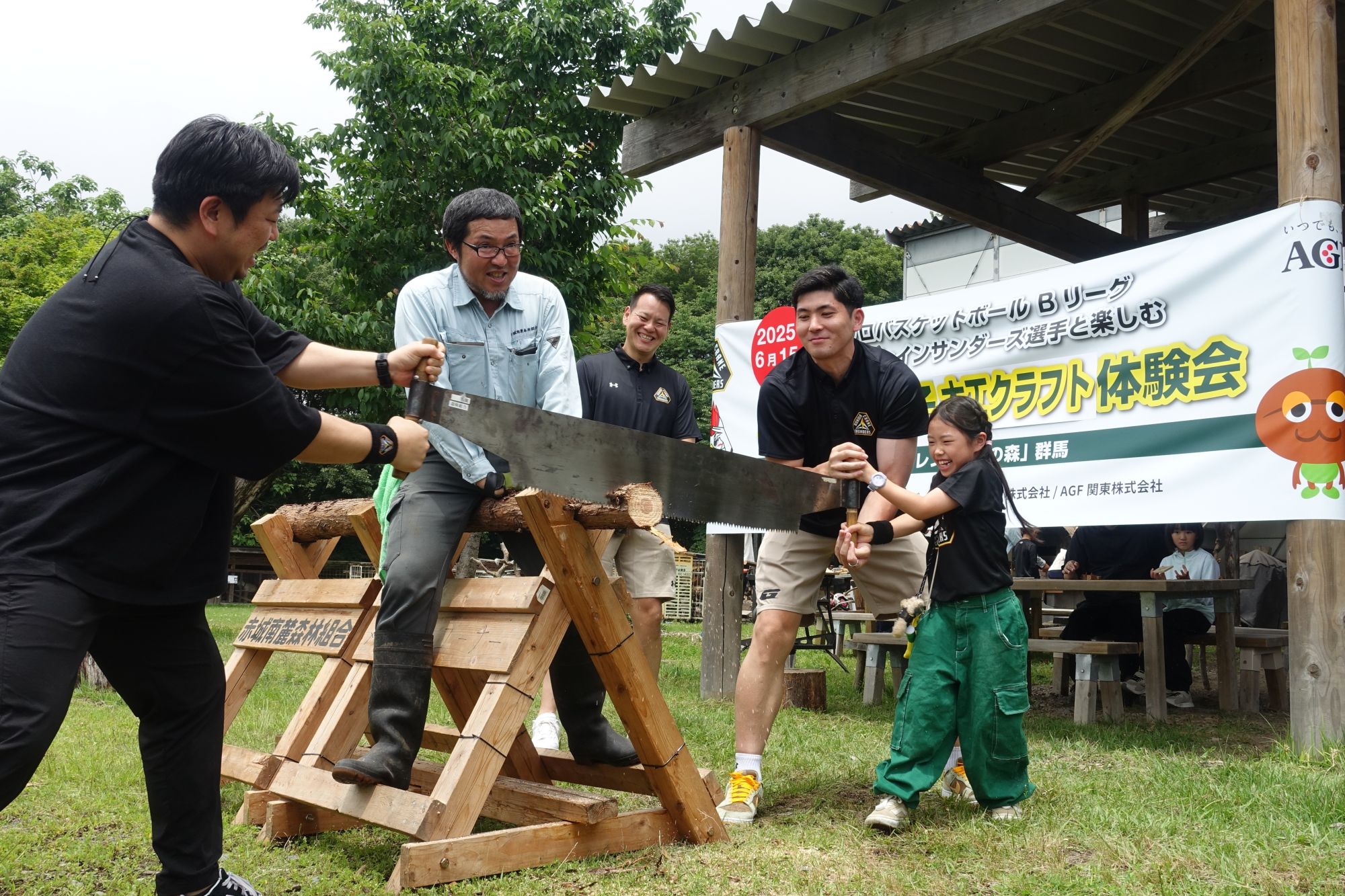 細川選手(右から2番目)と池田コーチ(同3番目)が丸太の切断体験に参加