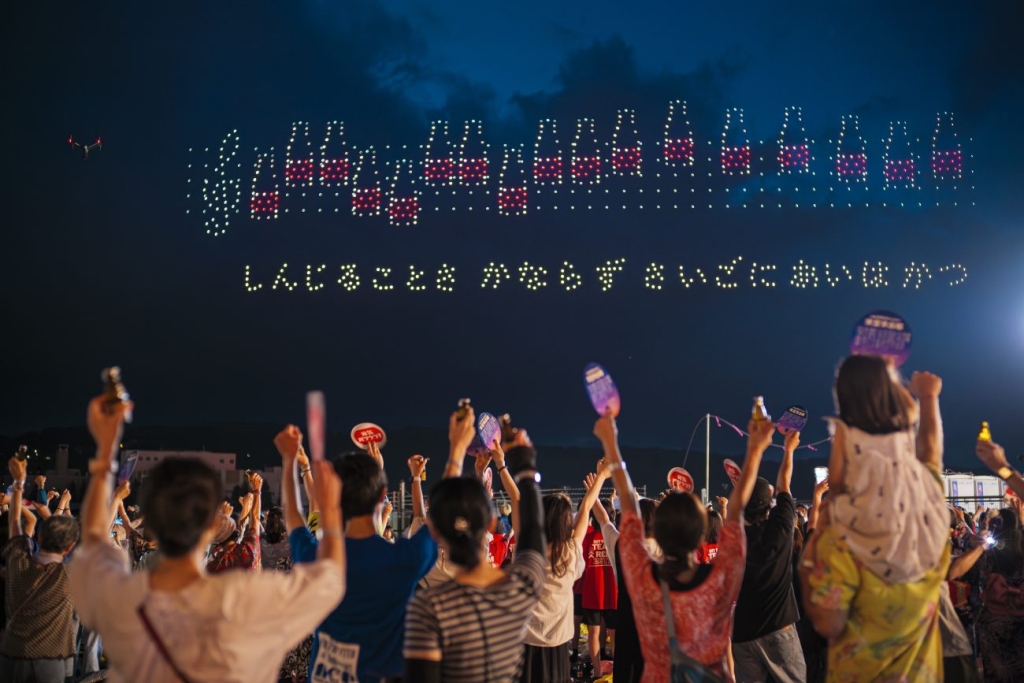 オロナミンCの形をした音符と、KANさんの「愛は勝つ」の歌詞に合わせて歌う来場者