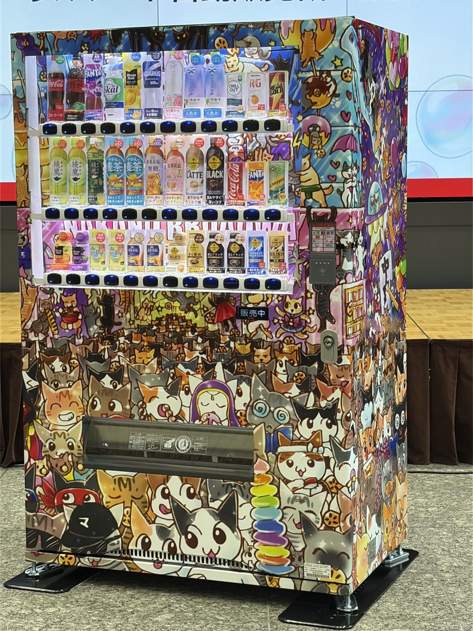 中川翔子さんがラッピングをデザインしたオリジナル自販機、中野ブロードウェイに入っていく猫たちがぎっしり描きこまれている