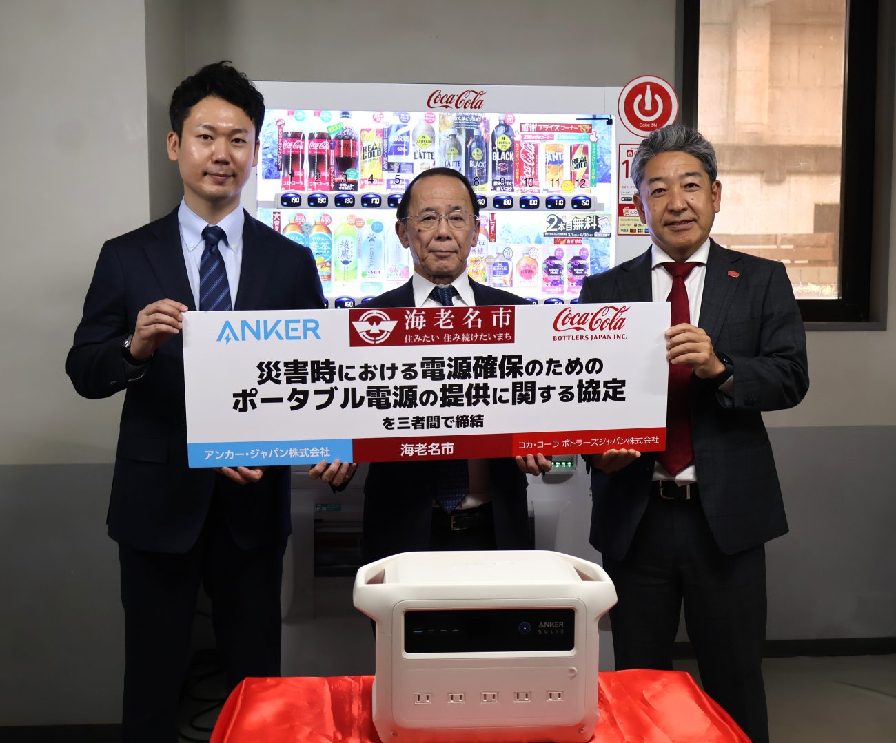 コカ・コーラボトラーズ締結式、自販機の前で（左から、アンカー・ジャパン猿渡代表取締役CEO、内野市長、久保氏）