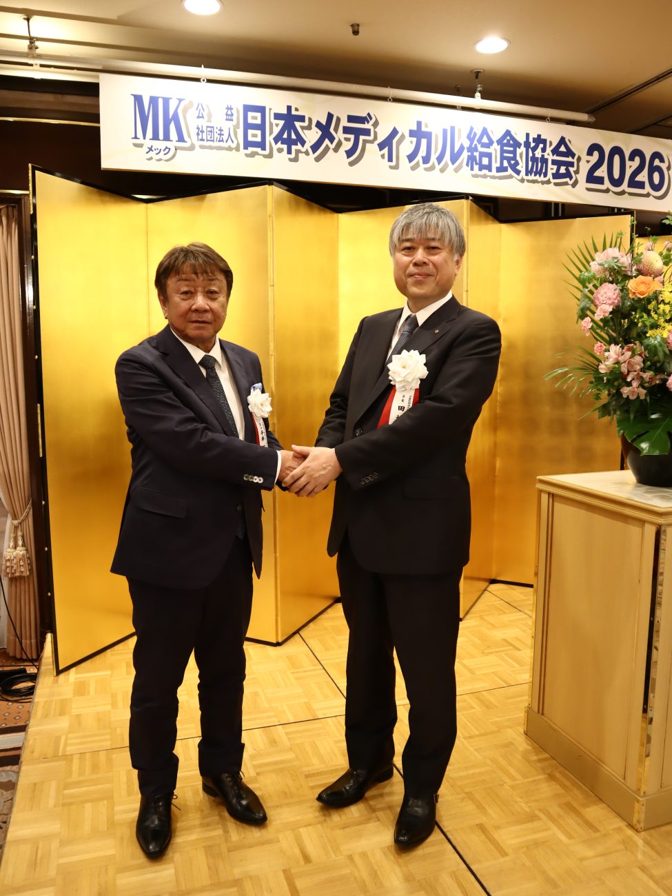 握手を交わす田村会長(右)と平井英司前会長