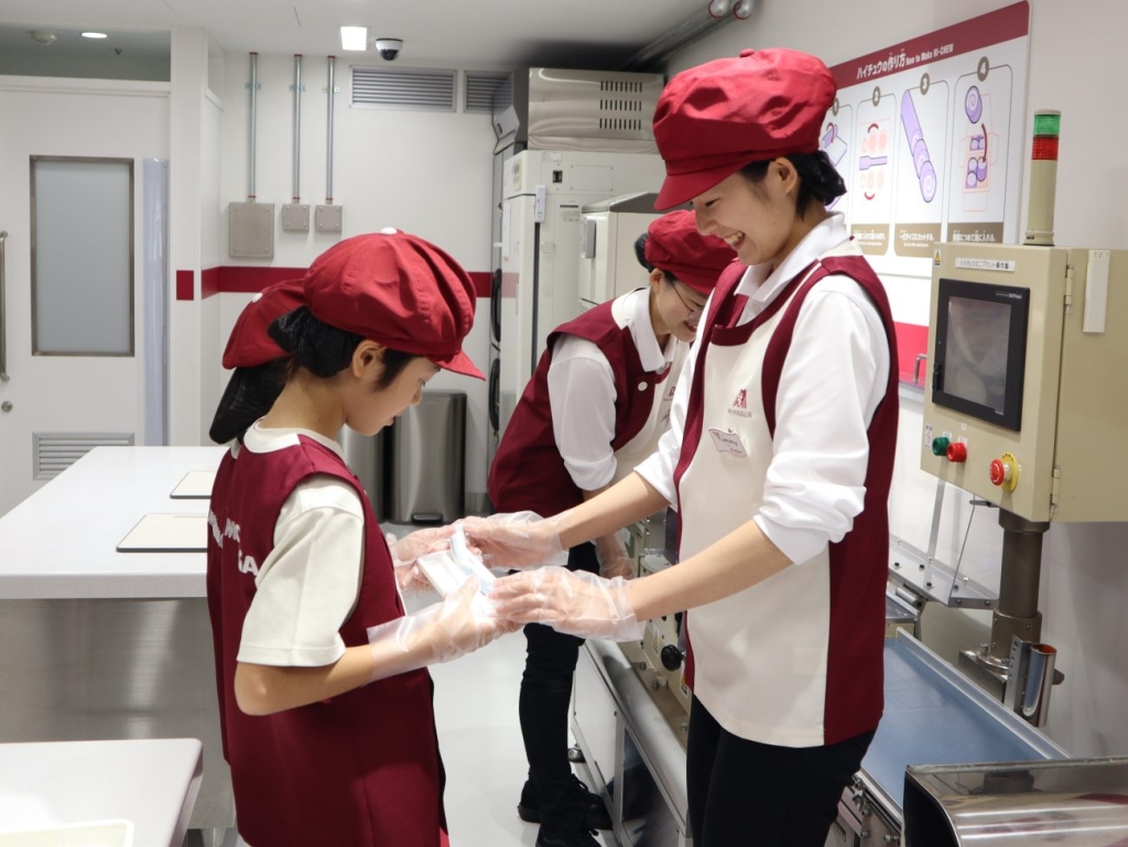 ハイチュウのシートを伸ばすスーパーバイザーと子ども