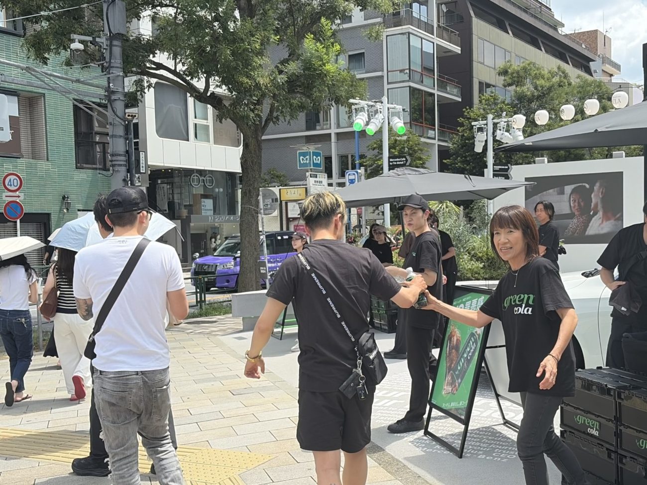 「green cola」を来場者に手渡すアサヒ飲料の近藤佳代子社長（右）