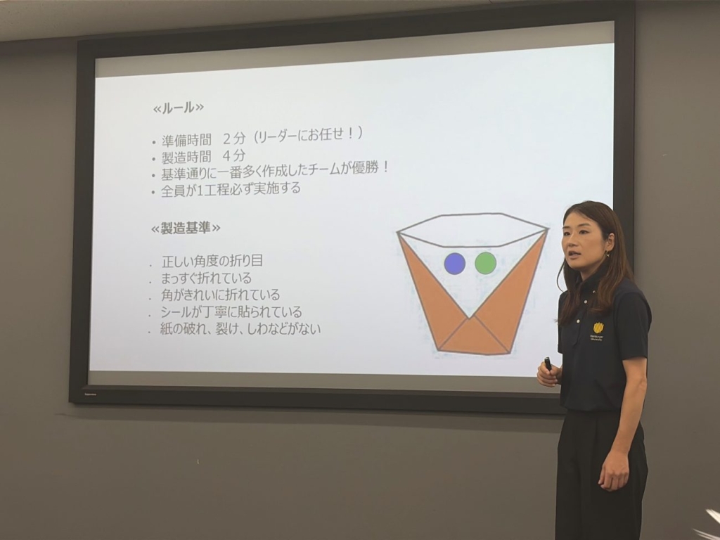 記者向けの研修を進行するハンバーガー大学の佐藤三恵子氏。折り紙で作る「紙コップ」のルールや製造基準を説明した
